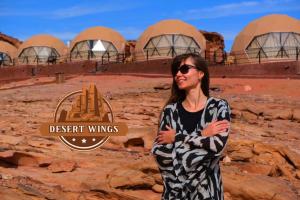 a woman standing in front of a desert wings building at RUM WINGS BUBBLES lUXURY CAMP in Wadi Rum