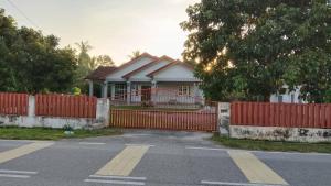 a house with a red fence in front of it at Merbok Little Bungalow in Kampong Merbok +12 photos