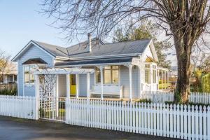 a small white house with a white fence at Picture Perfect in the heart of the Village in Greytown