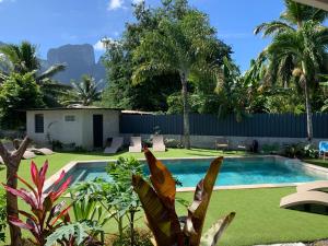 a backyard with a swimming pool and green grass at Tiki Ora Lodge - VARUA in Bora Bora