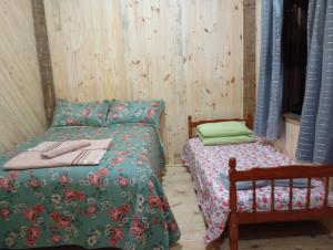 ein Schlafzimmer mit einem Bett und einem kleinen Bett und einem Stuhl in der Unterkunft Bangalô com cozinha Refúgio das borboletas in Itatiaia