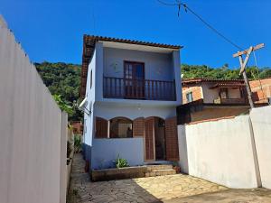 a white house with a porch and a balcony at Casa Aconchegante in Paraty