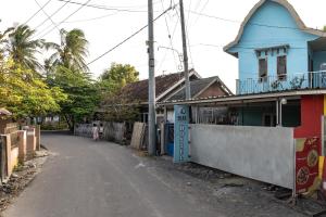 a street with a blue building on the side of a road at Ekas Loka Surf Hostel in Ekas