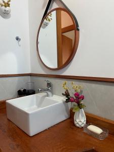 a bathroom sink with a mirror and a vase of flowers at Canto das Bromélias - Visconde de Mauá in Resende +11 photos