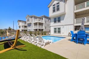 a pool with chairs and a hammock next to a house at 4057 - Fairways Seaspray in Kitty Hawk Beach +66 photos