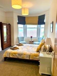 1 dormitorio con 1 cama grande, sillas y ventanas en Caroline's House, en Swanage