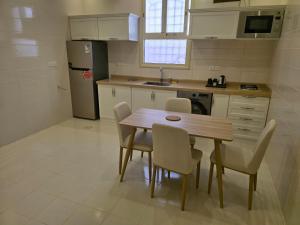 a kitchen with a table and chairs and a refrigerator at Rove Appartments in Taif