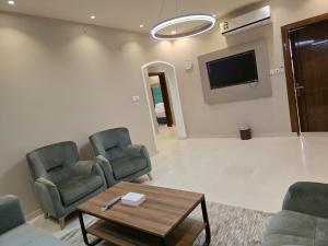 a living room with chairs and a table and a tv at Rove Appartments in Taif