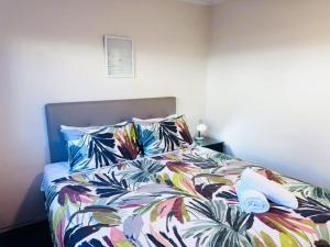 a bed with a colorful comforter and two pillows at Merivale Court Family Suit-Unit 4 in Christchurch +10 photos