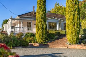 a house with cypress trees in front of it at Tasman Holiday Parks Picton in Picton