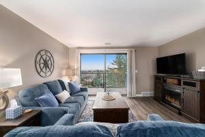a living room with a blue couch and a tv at Beautiful Lake View Golf Course Condo in Traverse City