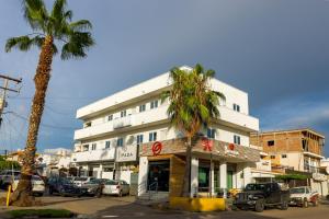 a white building with a palm tree in front of it at Comodo depa vacacional in Mazatlán