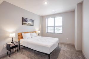 a white bedroom with a bed and a window at CozySuites at the Banks gym pool 09 in Cincinnati