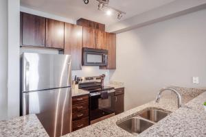 a kitchen with stainless steel appliances and wooden cabinets at CozySuites at the Banks gym pool 09 in Cincinnati