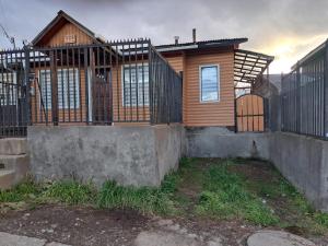 a wooden house with a gate and a fence at La chica in Coihaique