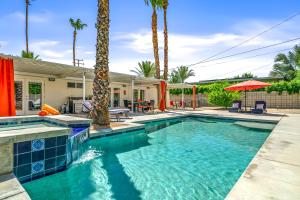a swimming pool in front of a house with palm trees at Palm Springs Home with a Resort Style Backyard -Joy pool hot tub views in Palm Springs