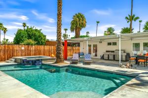 a swimming pool in a yard with two chairs and a house at Palm Springs Home with a Resort Style Backyard -Joy pool hot tub views in Palm Springs
