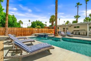 a swimming pool with lounge chairs and a fence at Palm Springs Home with a Resort Style Backyard -Joy pool hot tub views in Palm Springs