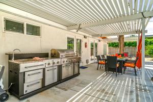 an outdoor kitchen with a grill and a table at Palm Springs Home with a Resort Style Backyard -Joy pool hot tub views in Palm Springs +34 photos