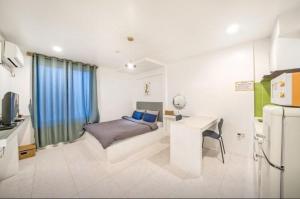 a bedroom with a bed and a desk and a refrigerator at Jeryeong Forest Pension in Gapyeong