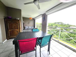 a dining room with a table and chairs and a balcony at Orchidée, Spacieux & Vue mer in Les Trois-Îlets