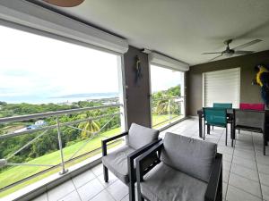a room with a balcony with a table and chairs at Orchidée, Spacieux & Vue mer in Les Trois-Îlets