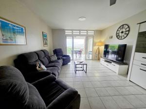a living room with a couch and a tv at Orchidée, Spacieux & Vue mer in Les Trois-Îlets