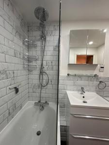 a white bathroom with a tub and a sink at Spacious 3 Bed Apartment in Central Romford just 5 mins to Elizabeth Line for Families Friends and Contractors in Romford