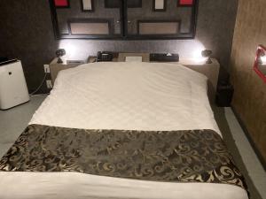 a bedroom with a large white bed with a brown blanket at ホテルアクアAdult Only in Hiroshima
