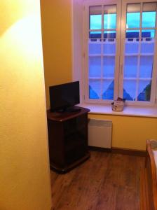 a living room with a tv and two windows at Les Lilas Roses in Chamouilley