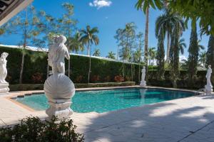 a statue next to a swimming pool with palm trees at Young Mansion Steps To The Beach in Hollywood