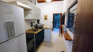 a kitchen with a white refrigerator and a sink at Bangalô no Sítio Cantal in Piracaia