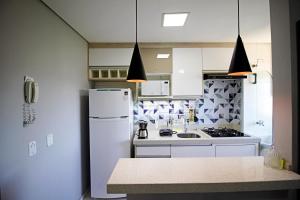 コチアにあるApartamento Ao lado Animalia Park com piscina e estacionamentoの白い冷蔵庫とシンクのあるキッチン