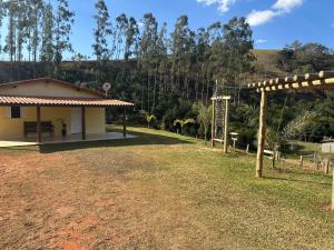 a small house in a field with a hill in the background at Casa de Campo Sitio com tranquilidade in Cunha
