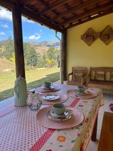 a table with plates and cups on top of it at Casa de Campo Sitio com tranquilidade in Cunha