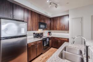 a kitchen with wooden cabinets and a stainless steel refrigerator at CozySuites at the Banks gym pool 16 in Cincinnati +19 photos