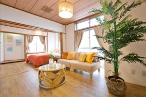 a living room with a couch and a palm tree at cuculu MAEJIMA 7F in Tomari