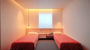 a room with two beds and a desk and a window at Nagoya Premium Hotel in Inazawa