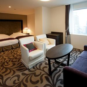 大阪Hotel Granvia Osaka-JR Hotel Group的酒店客房带两把椅子、一张桌子和一张床