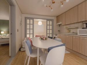 a kitchen and dining room with a white table and chairs at YanghwaStay in Seoul