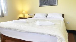a large white bed with two white towels on it at Surya Villa Guesthouse in Auroville