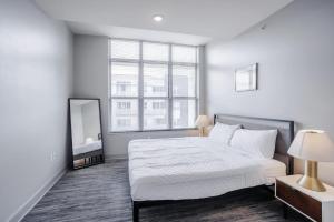 a white bedroom with a large bed and a mirror at TWO CozySuites at the Banks with Pool 17 in Cincinnati