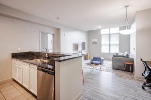 an apartment kitchen with a sink and a living room at TWO CozySuites at the Banks with Pool 17 in Cincinnati