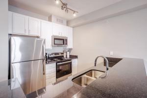 une cuisine avec des armoires blanches et un réfrigérateur en acier inoxydable dans l'établissement CozySuites at the Banks gym pool 10, à Cincinnati 17 autres photos