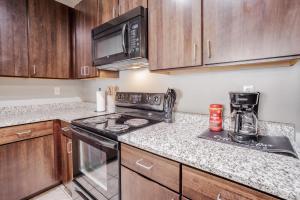 a kitchen with wooden cabinets and a stove top oven at CozySuites at the Banks gym pool 15 in Cincinnati +16 photos