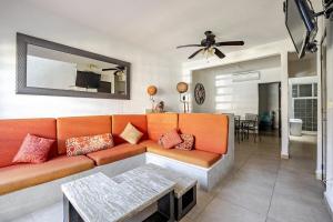 a living room with an orange couch and a dining room at Spacious house with Acapulco club in Acapulco