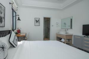 - une chambre avec un grand lit blanc et un lavabo dans l'établissement Roy-Sanya Bay Coconut Dream Corridor, à Shuijiao