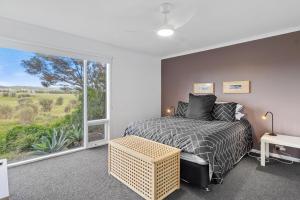 a bedroom with a bed and a large window at Bungala Cottage 28 Jetty Road in Normanville