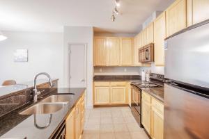 a kitchen with wooden cabinets and a stainless steel refrigerator at CozySuites at the Banks gym pool 06 in Cincinnati +13 photos