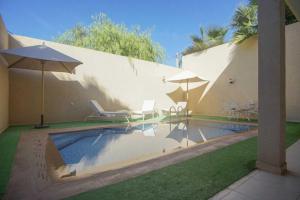 a swimming pool with two chairs and umbrellas at Villa B with a private pool in Oulad Ikhia